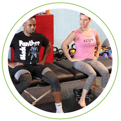 Two teammates doing mobility exercises on a bench